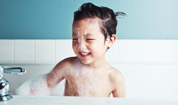 Boy smiling while taking a bubble bath