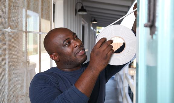 Image of man installing weather-stripping on his home's windows