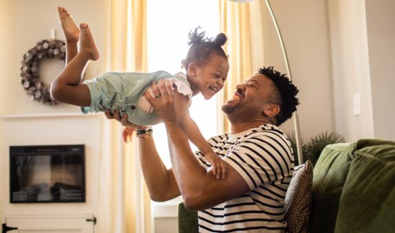 Image of father and daughter playing in living room