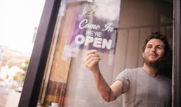 Image of small business owner flipping over the open sign
