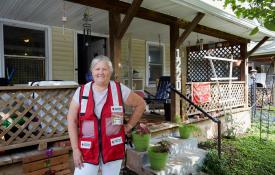 Image of: Red Cross volunteer standing in front of her home