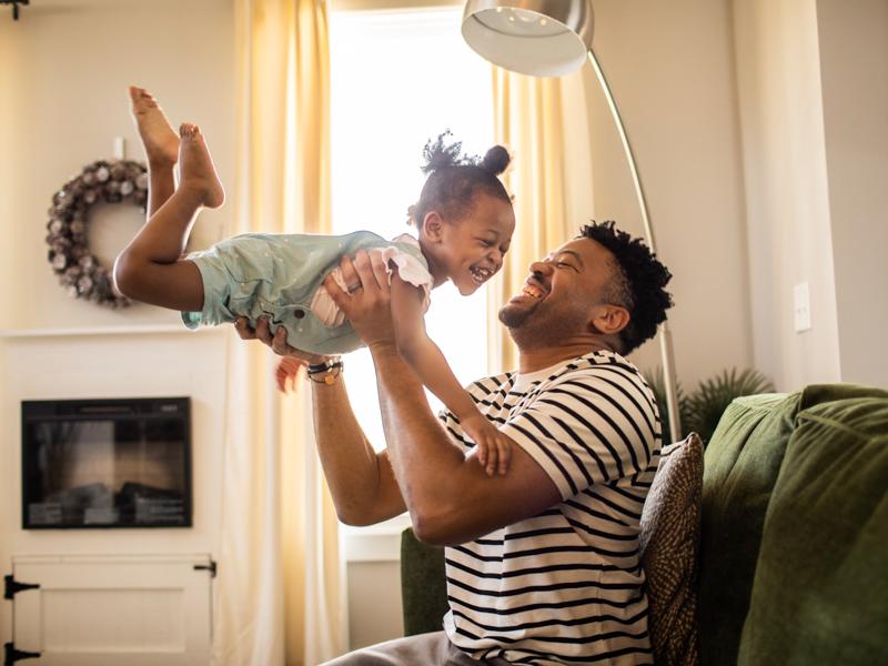 Image of father and daughter playing in living room