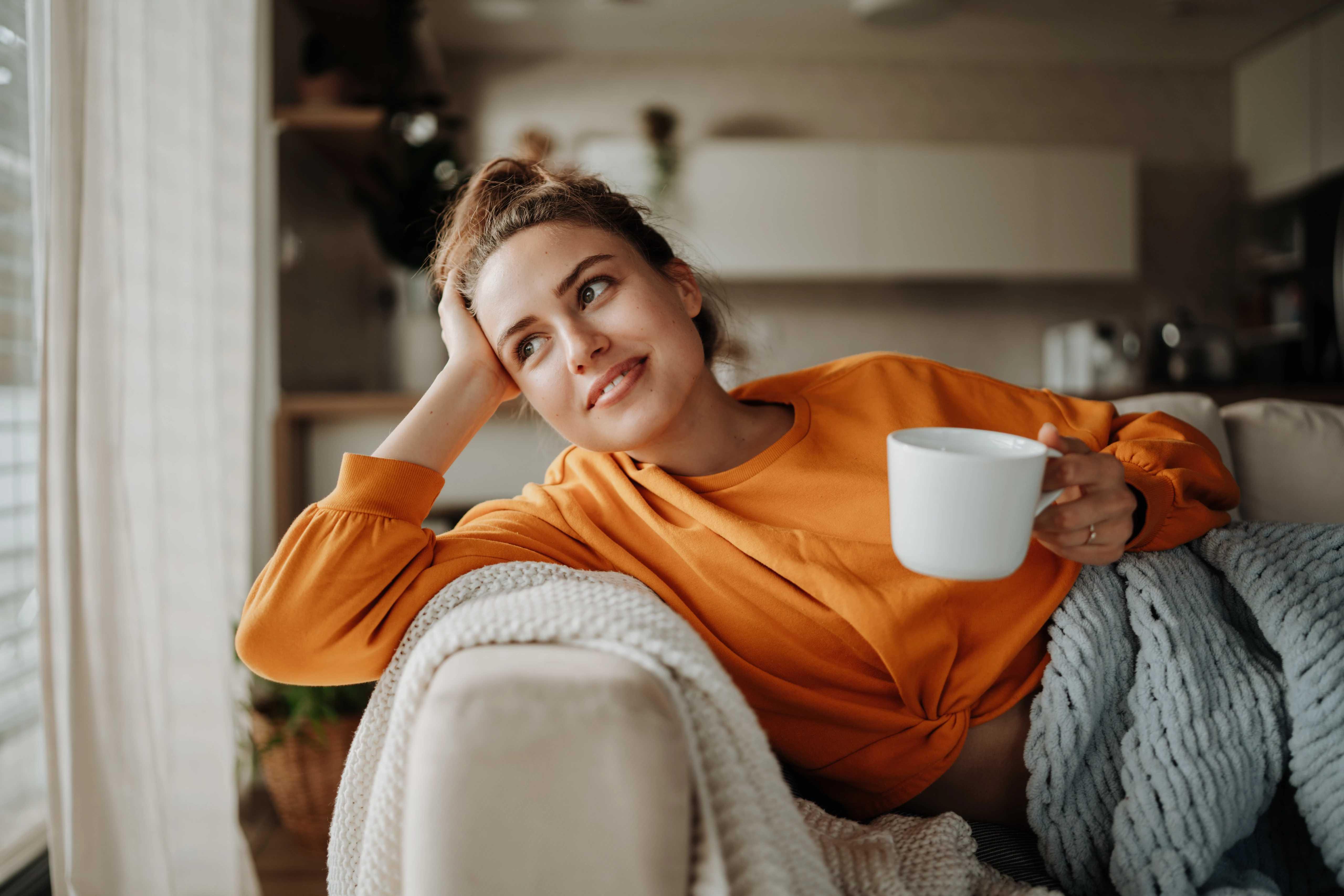 Woman in orange sweater on couch