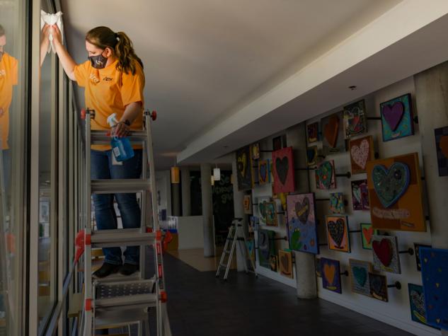 Image of Spire volunteer standing on ladder and cleaning windows